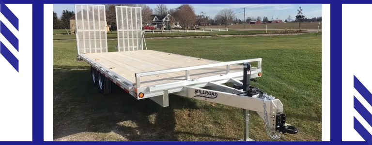 Custom flatdeck aluminum trailer by Millroad Manufacturing parked on grass with dual ramps and durable frame.